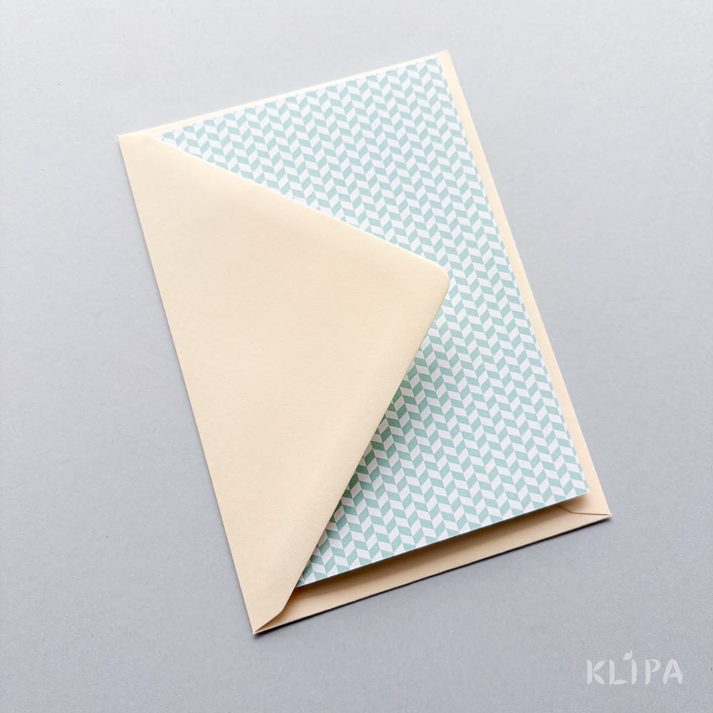 Beige envelope partially open, revealing a blue chevron-patterned card inside.